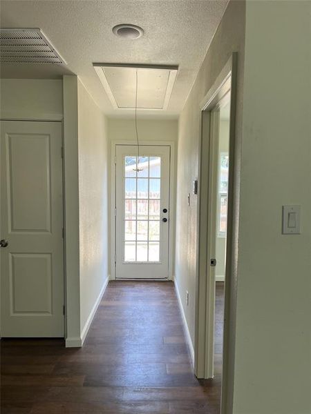 Hallway featuring dark wood-finish flooring, light-colored walls, and a white paneled door