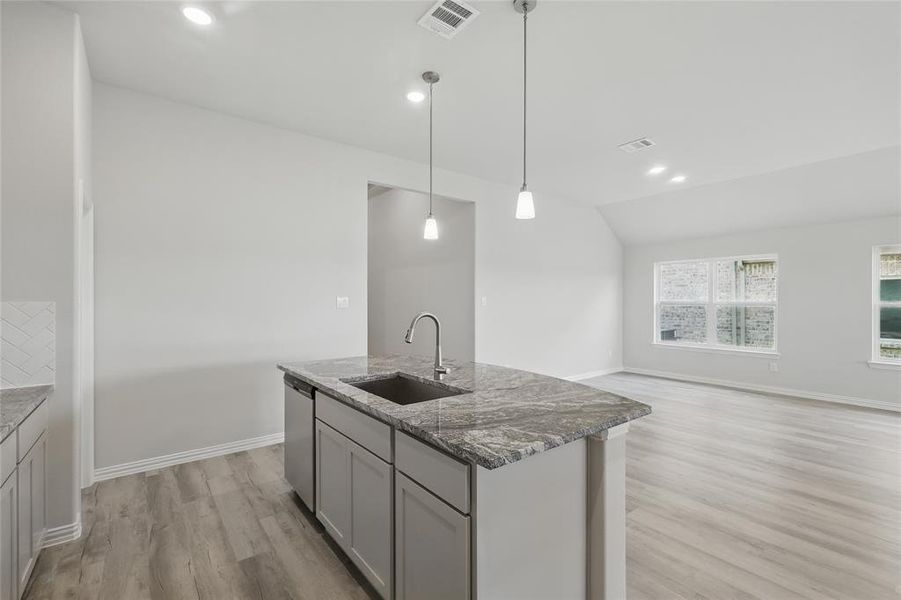 Kitchen featuring a sink, stainless steel dishwasher, light wood-type flooring, stone countertops, and baseboards Kitchen featuring a sink, stainless steel dishwasher, light wood-type flooring, stone countertops, and baseboards