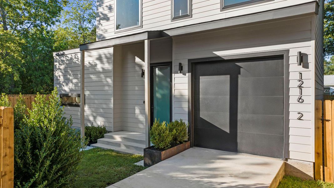 Entrance to property featuring an attached garage, stone landcape pavers, native landscaping Entrance to property featuring an attached garage, stone landcape pavers, native landscaping