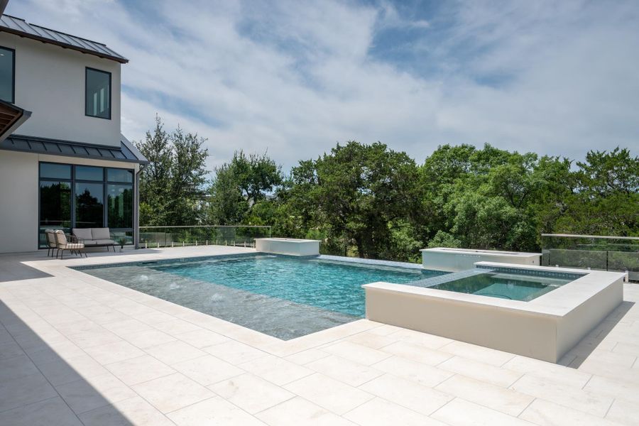 An inviting in-ground pool and integrated spa provide a serene outdoor escape amidst lush greenery.