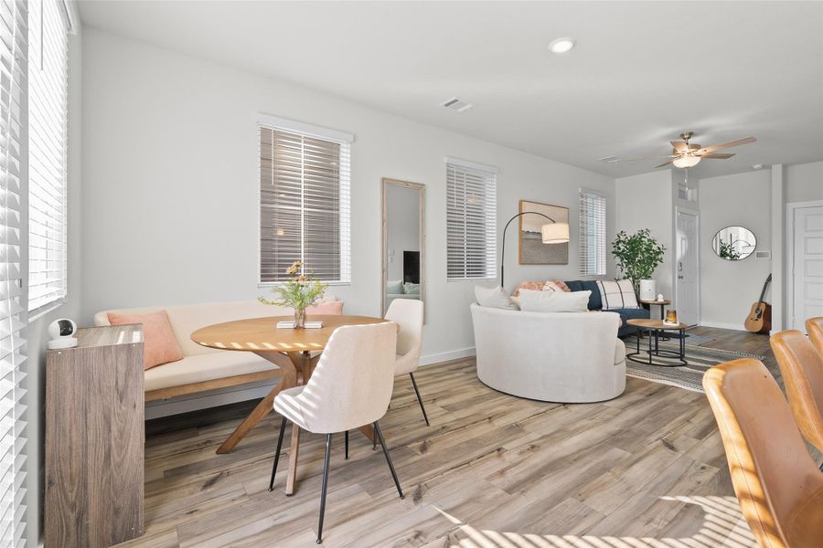 This photo showcases a bright, open living space with modern decor. It features wood flooring, a cozy seating area with a round table, and ample natural light from multiple windows. The room is stylishly furnished with a mix of neutral tones and accent pieces, creating a warm, inviting atmosphere.