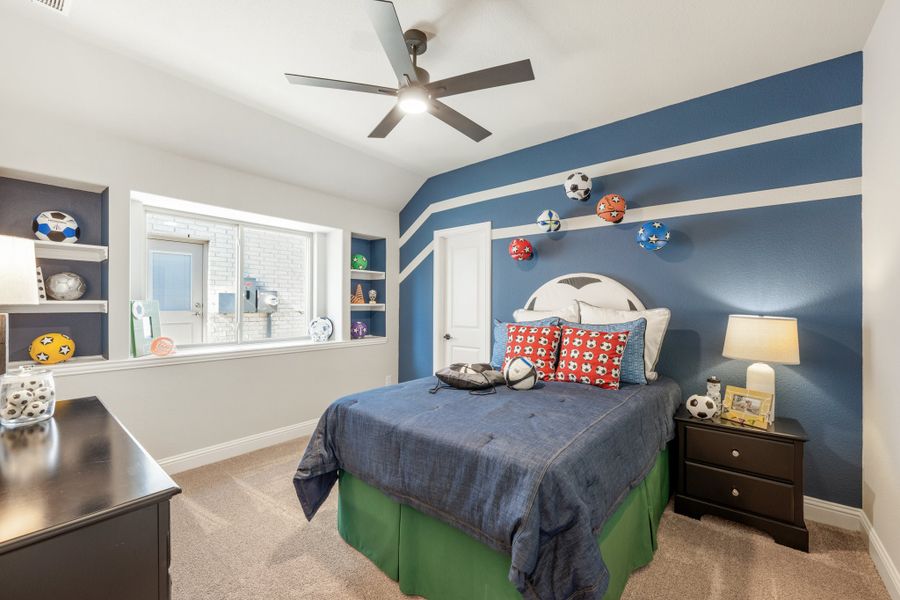Kids' bedroom with blue accent wall, sports-themed decor, built-in shelves, and ceiling fan