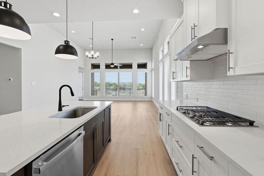 Dual tone kitchen with two tone color scheme, light wood-type flooring, stainless steel appliances, light stone countertops, and healthy amount of natural light