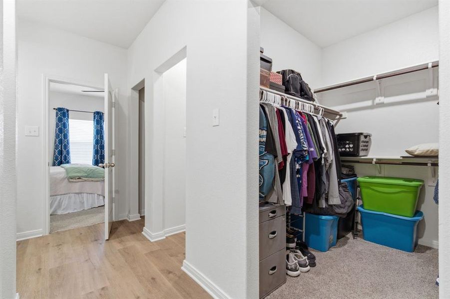 Hallway featuring light wood-style flooring and a closet with shelving and hanging rods