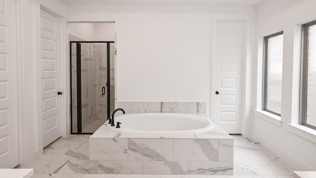 Bathroom with a garden tub, marble finish floors, a shower stall, and baseboards Bathroom with a garden tub, marble finish floors, a shower stall, and baseboards