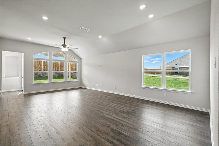 Unfurnished living room featuring plenty of natural light, a ceiling fan, lofted ceiling, dark wood finished floors, and recessed lighting