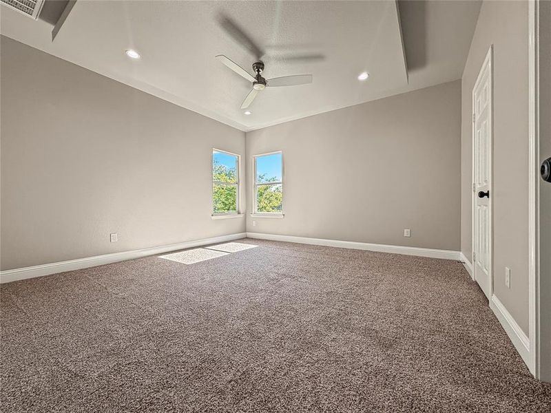 Spacious room featuring vaulted ceilings, recessed lighting, a ceiling fan, two windows, and neutral carpeting Spacious room featuring vaulted ceilings, recessed lighting, a ceiling fan, two windows, and neutral carpeting