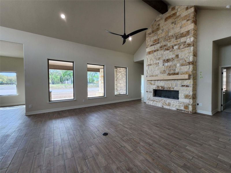 Unfurnished living room featuring a ceiling fan, dark wood-type flooring, lofted ceiling, and a fireplace