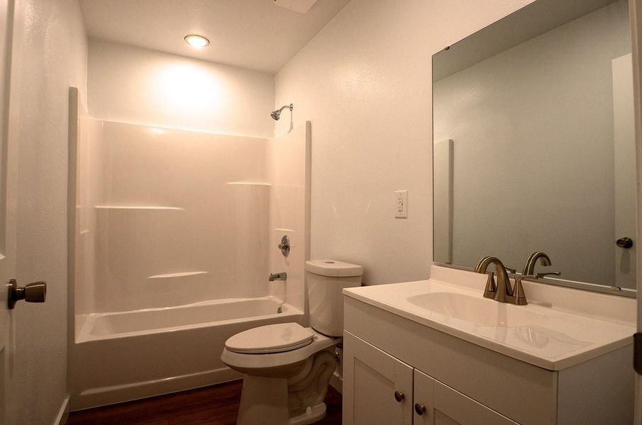 Bathroom featuring vanity,  shower combination, and dark wood-style floors