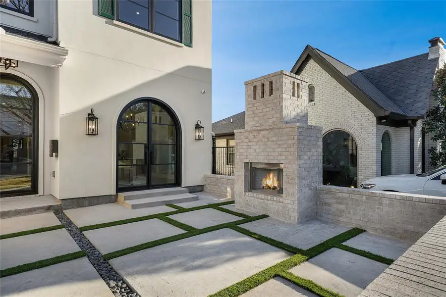 Property entrance with stucco siding, an outdoor brick fireplace, a chimney, and brick siding Property entrance with stucco siding, an outdoor brick fireplace, a chimney, and brick siding