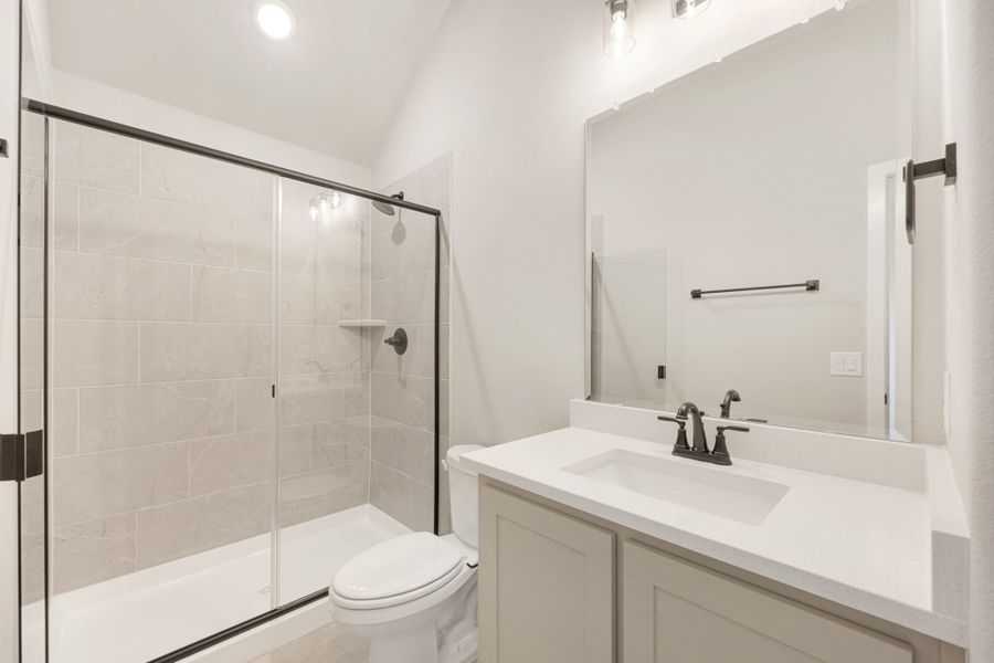 Bathroom with tile shower and glass door, single vanity with white countertop, and vaulted ceiling