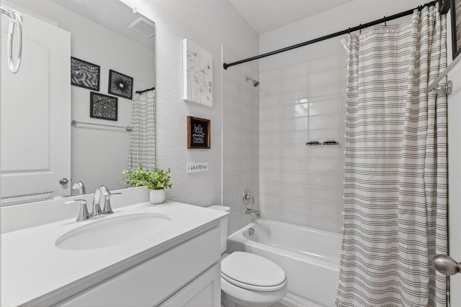 Full bath with vanity, shower / tub combo with curtain, and a textured wall Full bath with vanity, shower / tub combo with curtain, and a textured wall