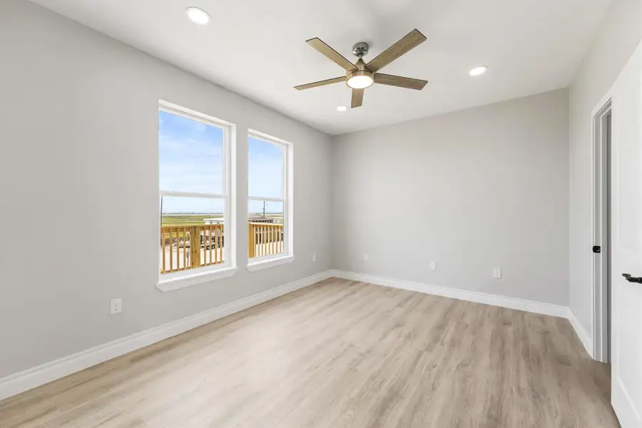 A bright and airy Primary Suite with light wood flooring, large windows offering a view, a ceiling fan, and recessed lighting. Perfect for a bedroom or office space. A bright and airy Primary Suite with light wood flooring, large windows offering a view, a ceiling fan, and recessed lighting. Perfect for a bedroom or office space.
