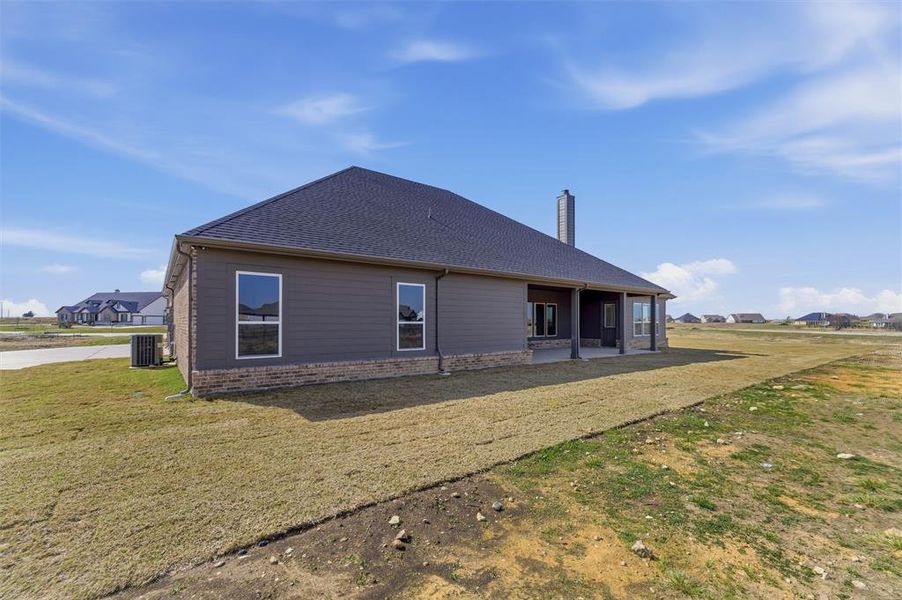 Back of house featuring brick siding, a patio area, a shingled roof, a yard, and a residential view Back of house featuring brick siding, a patio area, a shingled roof, a yard, and a residential view