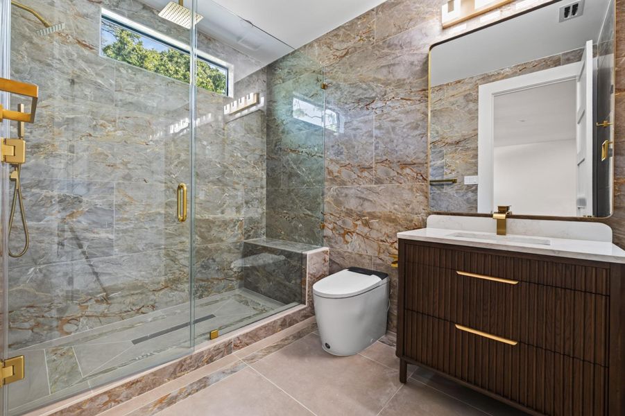 Beautifully finished secondary primary bath features a glass-enclosed shower and warm natural materials.