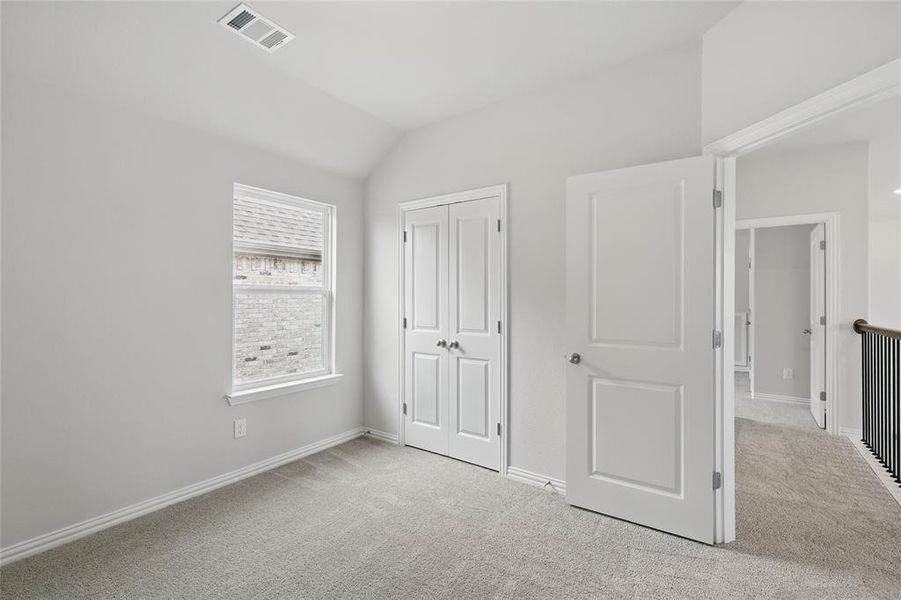 Unfurnished bedroom featuring light carpet, vaulted ceiling, and a closet