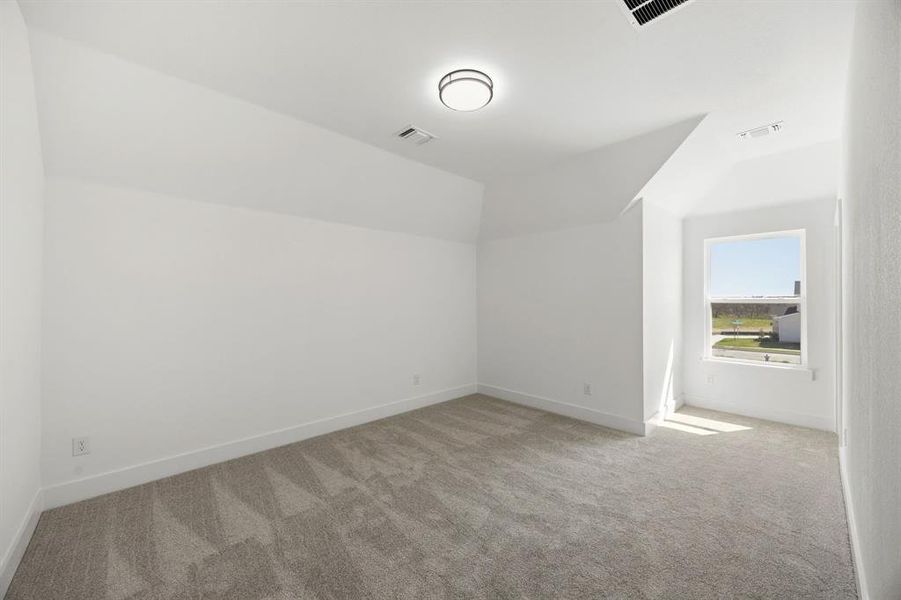 Bonus room with lofted ceiling and light colored carpet