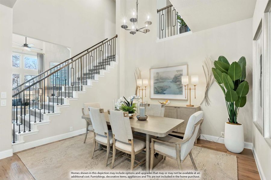 Dining room with high ceilings, wood floors, chandelier, and staircase with iron railings nearby Dining room with high ceilings, wood floors, chandelier, and staircase with iron railings nearby
