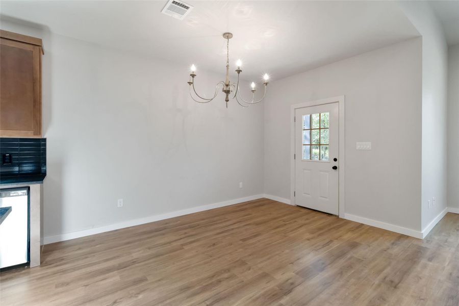Unfurnished dining area with a chandelier and light wood finished floors
