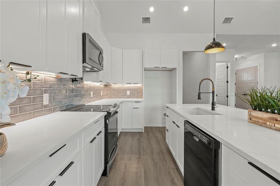 Kitchen with dishwashing machine, stainless steel microwave, range with electric cooktop, light wood-type flooring, and tasteful backsplash