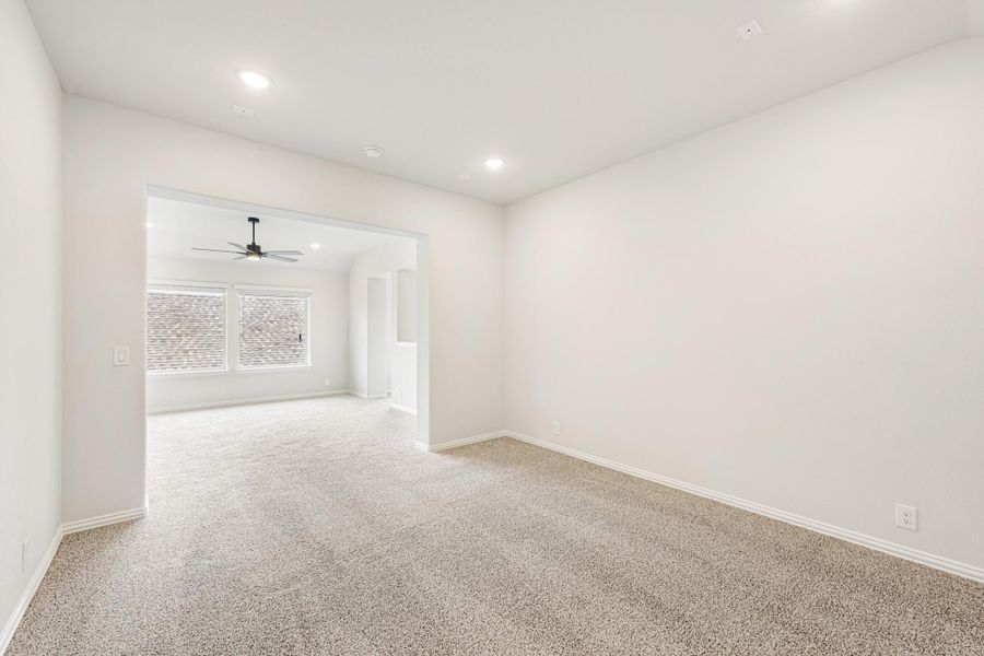Empty room with beige carpet, white walls, and open doorway leading to a second room with ceiling fan