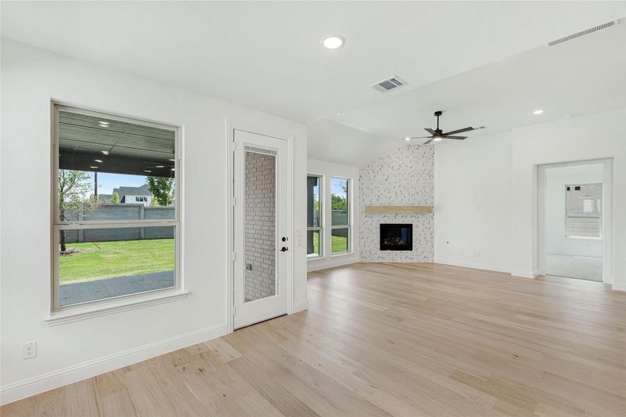 Open living room with light hardwood floors, fireplace with tile accent wall, and ceiling fan Open living room with light hardwood floors, fireplace with tile accent wall, and ceiling fan