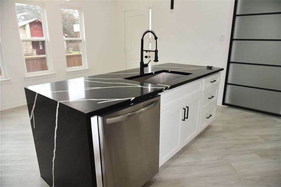 Kitchen featuring white cabinetry, dishwasher, sink, an island with sink, and light hardwood / wood-style floors