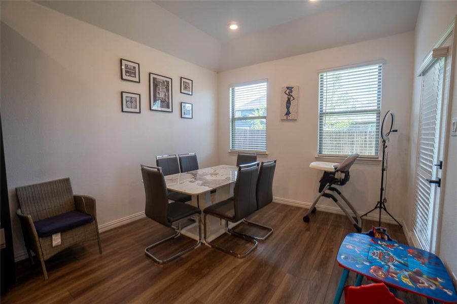 Spacious room featuring wood-finish flooring, recessed lighting, and multiple windows with blinds