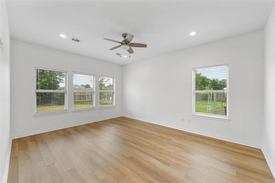 Bright interior space featuring wood-finish flooring, white walls, and multiple windows with blinds