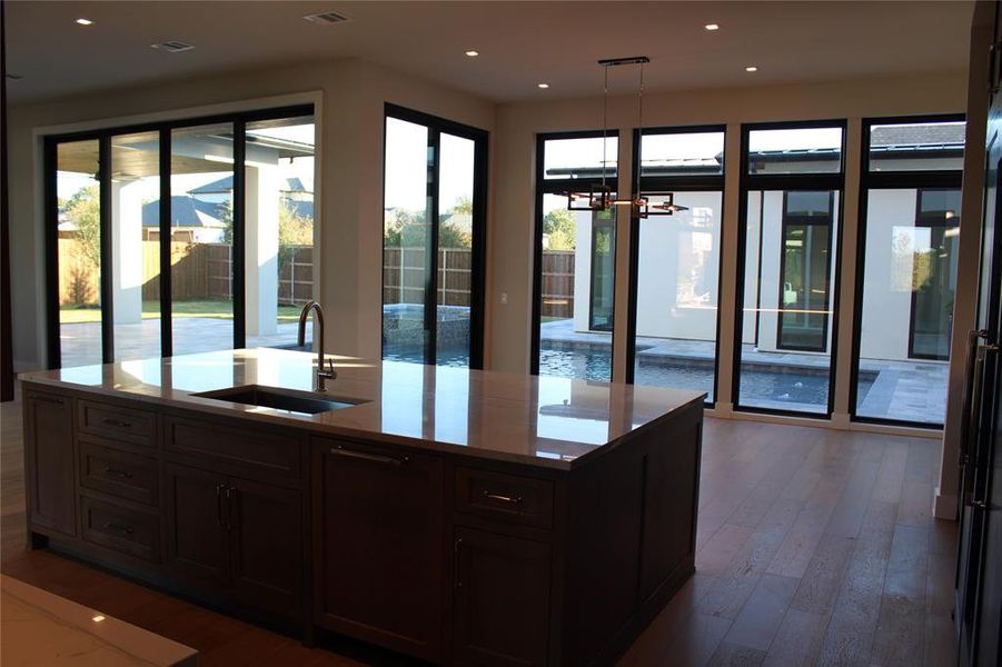 Kitchen featuring a kitchen island with sink, sink, an inviting chandelier, dark hardwood / wood-style floors, and hanging light fixtures