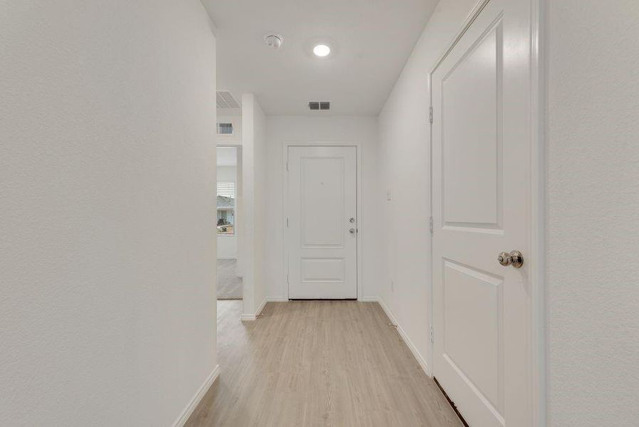 Hallway featuring light wood finished floors, visible vents, and baseboards