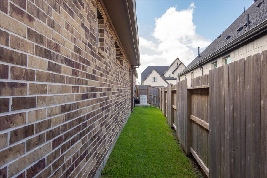 View of side of home from back yard to the front yard showing the Generac generator. Both sides of fencing each have their own gate entrance as well.