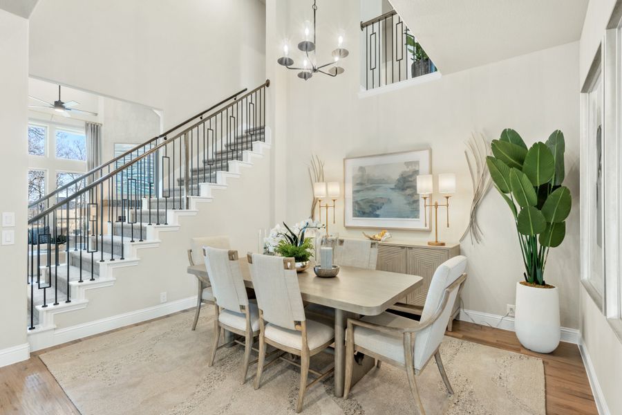Dining room with six-chair table, high ceilings, chandelier, and staircase with iron railing nearby Dining room with six-chair table, high ceilings, chandelier, and staircase with iron railing nearby