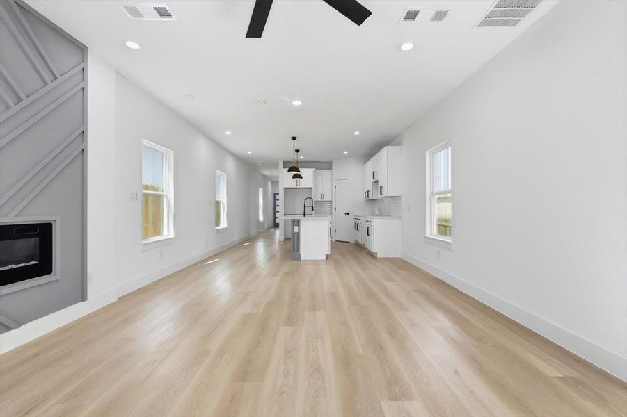Unfurnished living room featuring ceiling fan, light wood-type flooring, recessed lighting, and a glass covered fireplace