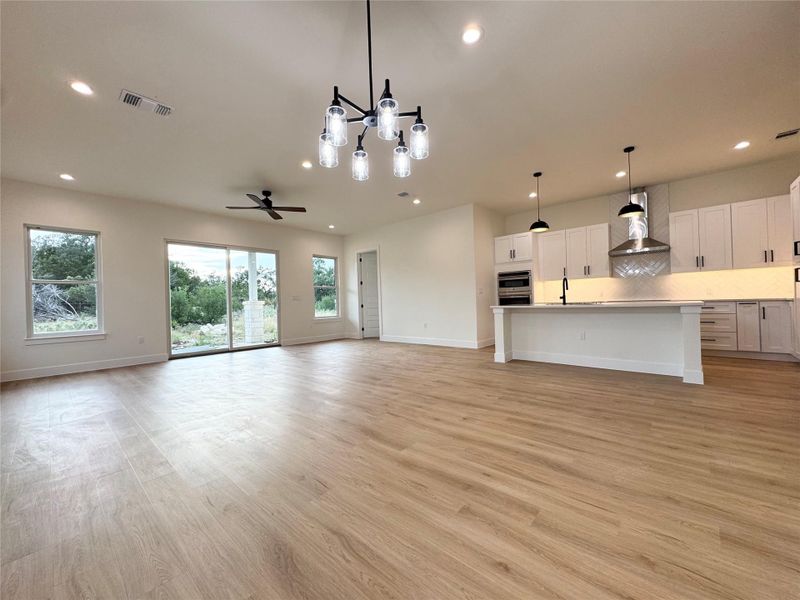 An open-concept living space blends seamlessly with a contemporary kitchen, illuminated by recessed lighting and a stylish chandelier. An open-concept living space blends seamlessly with a contemporary kitchen, illuminated by recessed lighting and a stylish chandelier.