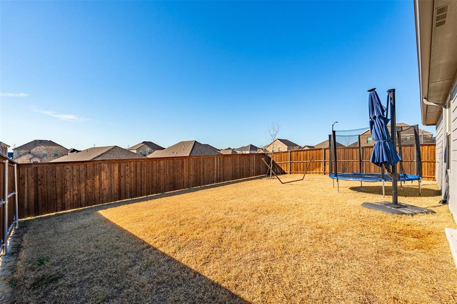 View of yard featuring a trampoline and a fenced backyard