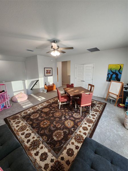 An inviting secondary living area features an elegant area rug over carpeting, offering a cozy retreat.