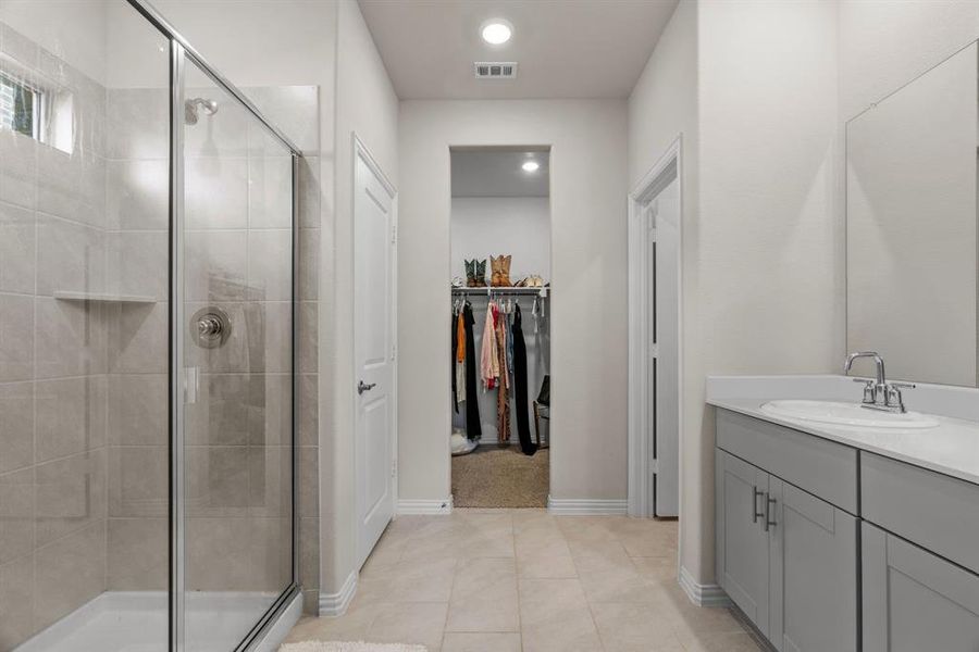 Full bath with a stall shower, vanity, a spacious closet, and light tile patterned flooring Full bath with a stall shower, vanity, a spacious closet, and light tile patterned flooring