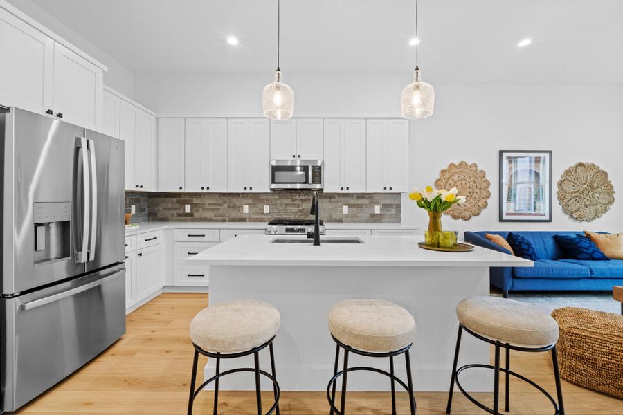 Kitchen with stainless steel appliances, a kitchen bar, open floor plan, a center island with sink, and decorative backsplash