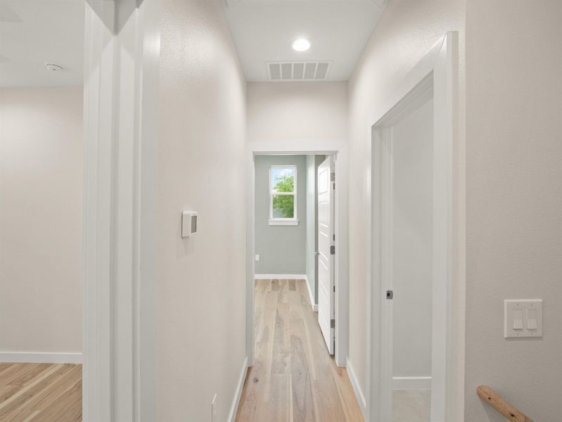 Hallway featuring wood-finish flooring, recessed lighting, and a neutral color palette
