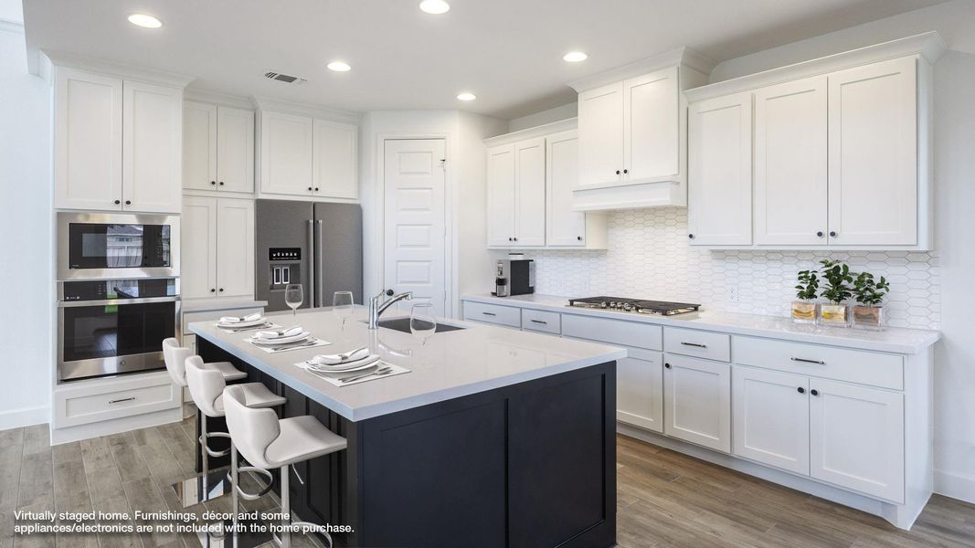 Kitchen with white cabinets, appliances with stainless steel finishes, a breakfast bar, light wood-style flooring, and light countertops Kitchen with white cabinets, appliances with stainless steel finishes, a breakfast bar, light wood-style flooring, and light countertops