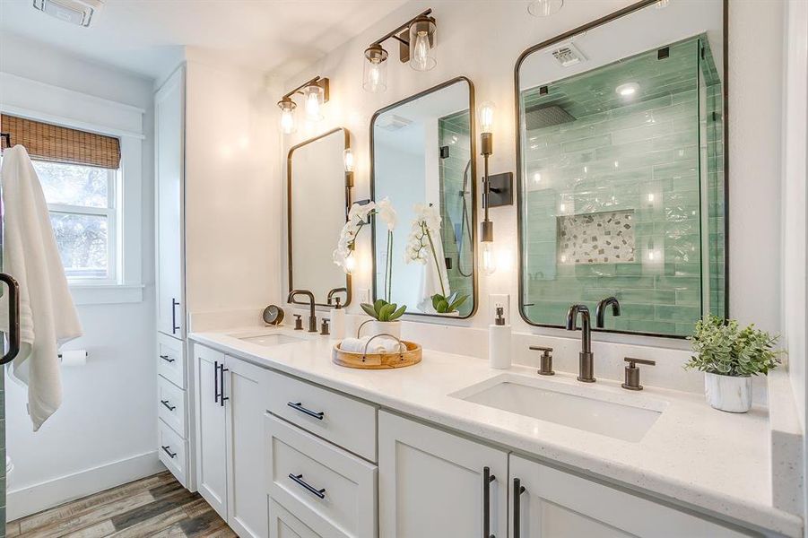 Full bath with double vanity, wood finished floors, and a stall shower