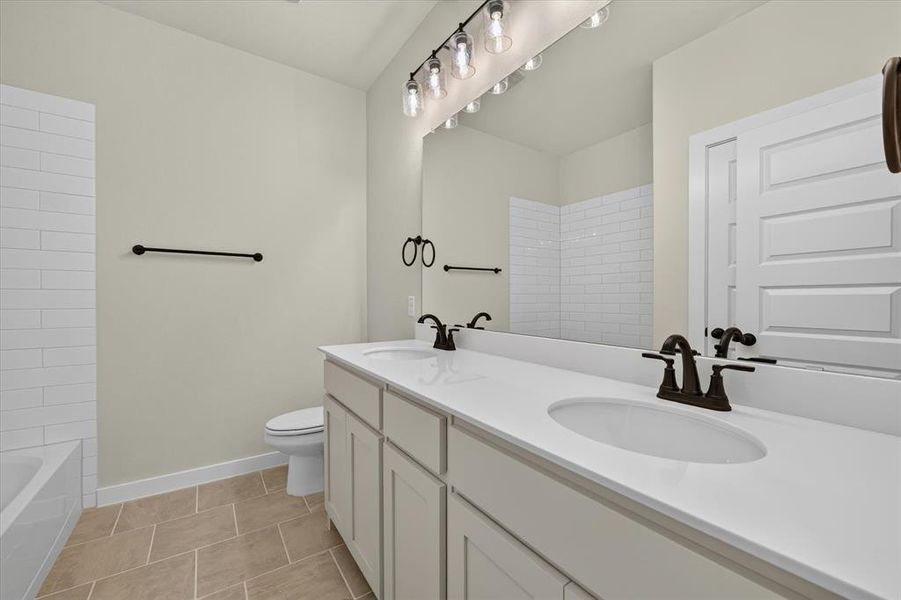 Bathroom featuring a dual vanity with white countertops, integrated sinks, and bronze-finish fixtures Bathroom featuring a dual vanity with white countertops, integrated sinks, and bronze-finish fixtures