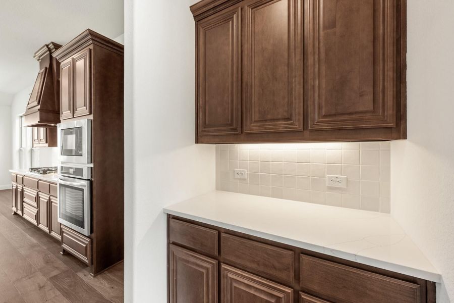Kitchen with dark wood cabinets, white quartz countertops, tile backsplash, and built-in double oven with microwave Kitchen with dark wood cabinets, white quartz countertops, tile backsplash, and built-in double oven with microwave