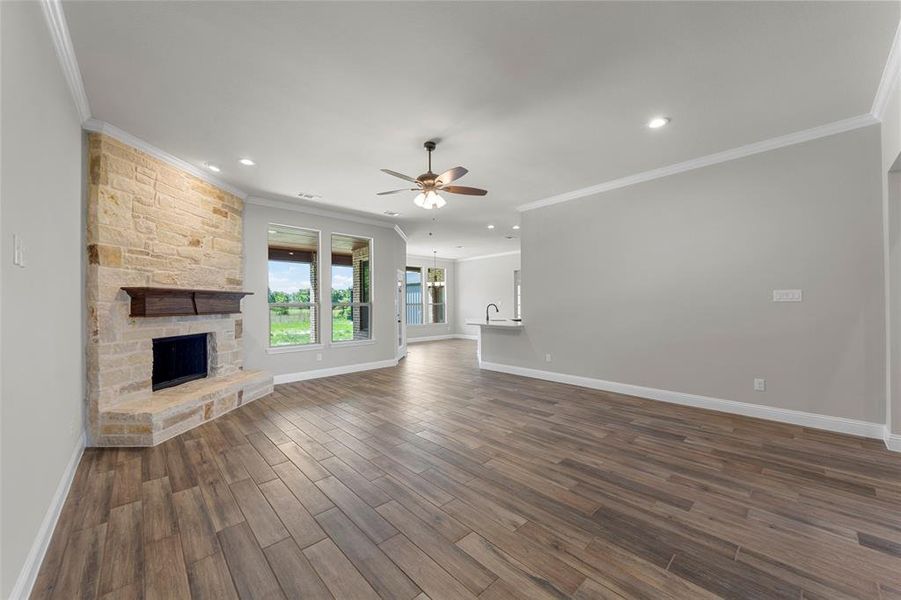 Unfurnished living room with a ceiling fan, ornamental molding, baseboards, a fireplace, and dark wood-style floors Unfurnished living room with a ceiling fan, ornamental molding, baseboards, a fireplace, and dark wood-style floors