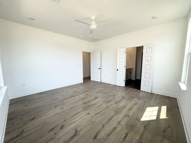 Unfurnished bedroom with dark wood-type flooring, a ceiling fan, and ensuite bath