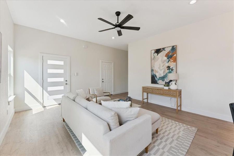 Living room with a ceiling fan, recessed lighting, and light wood-style floors
