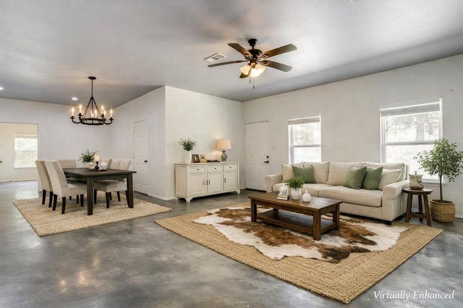Open-concept living and dining area featuring polished concrete flooring, white walls, and abundant natural light from multiple windows