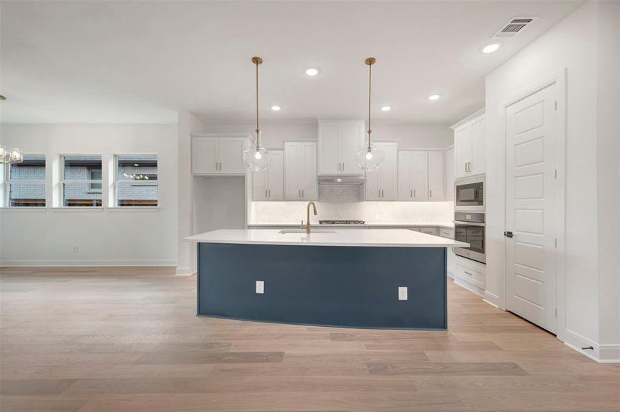 The kitchen features white cabinetry, a large kitchen island with a dark base and light countertop, and modern pendant lighting