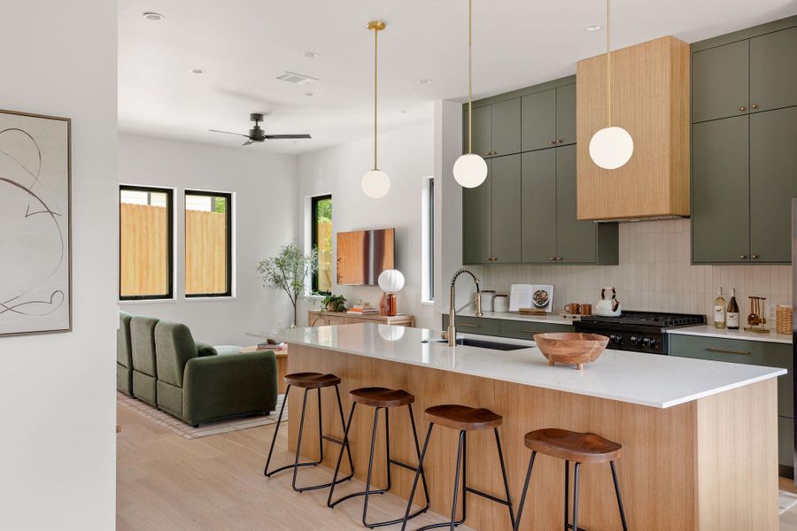 Kitchen with stove, open floor plan, light wood finished floors, light countertops, and backsplash Kitchen with stove, open floor plan, light wood finished floors, light countertops, and backsplash